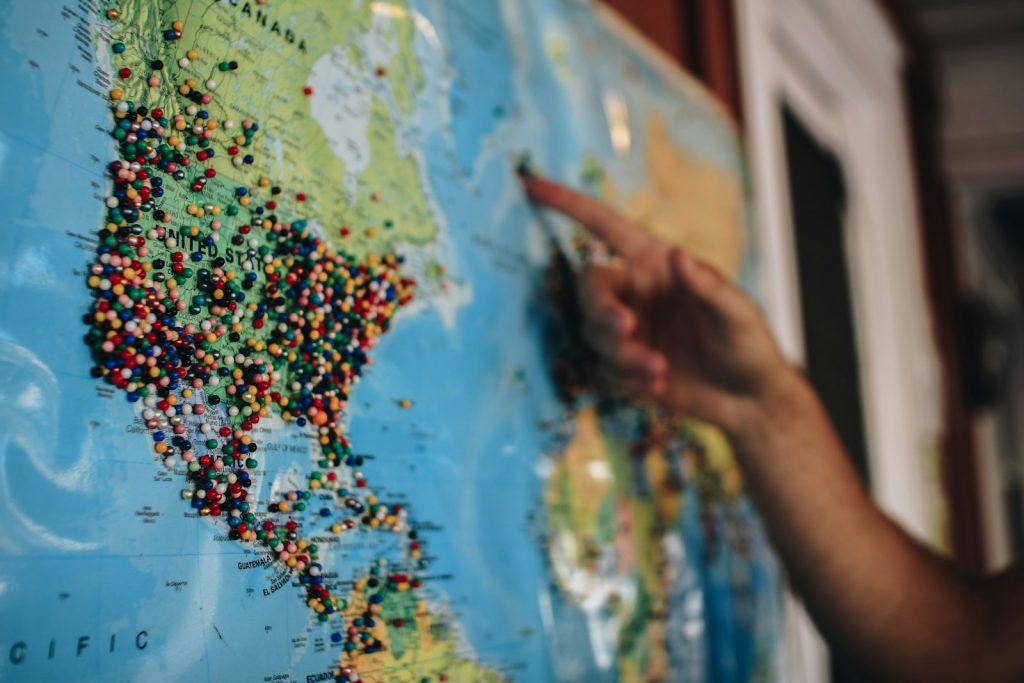 Person pointing at a world map with pins, representing a translation plugin comparison