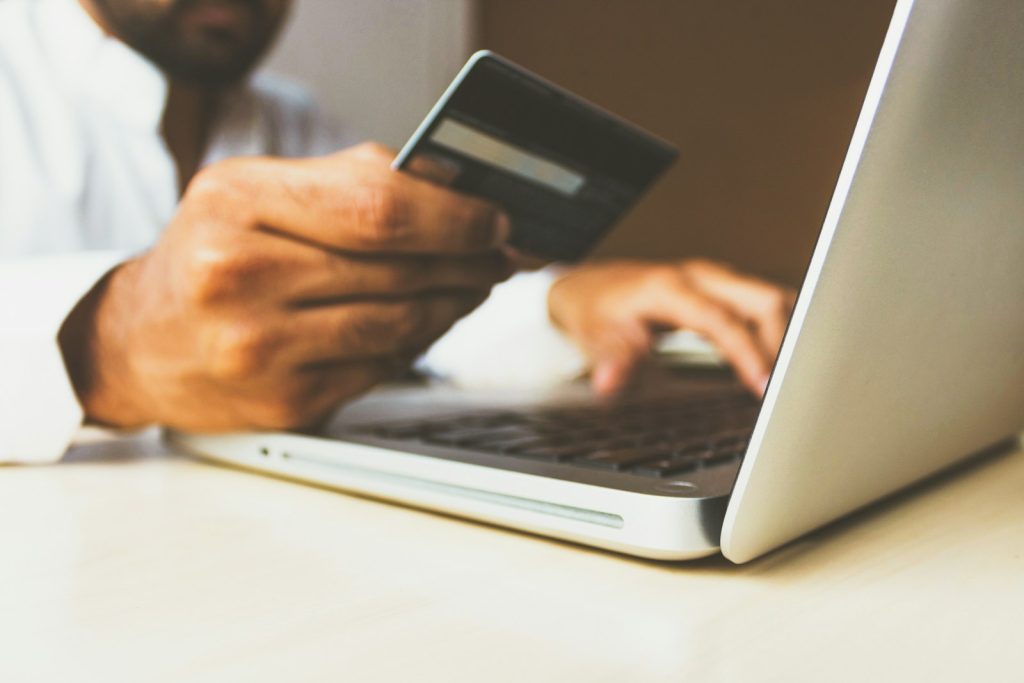 Person using laptop and holding a card representing WooCommerce checkout translation